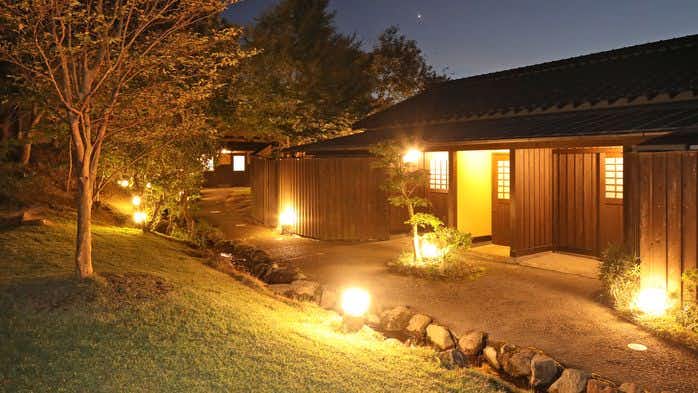 Oyado Daikonya: The low timber residence glowing across the evening garden.