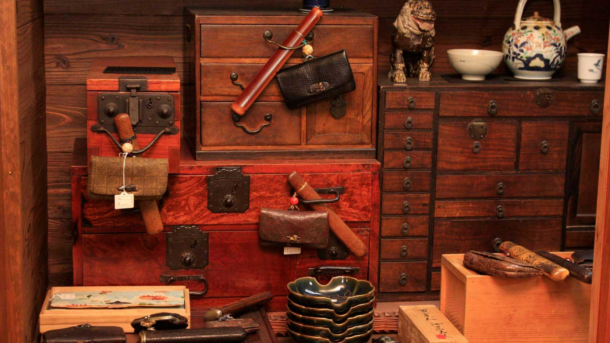 Ryokan Miyukiya with antique drawers and ceramic ornaments arranged against red timber walls.