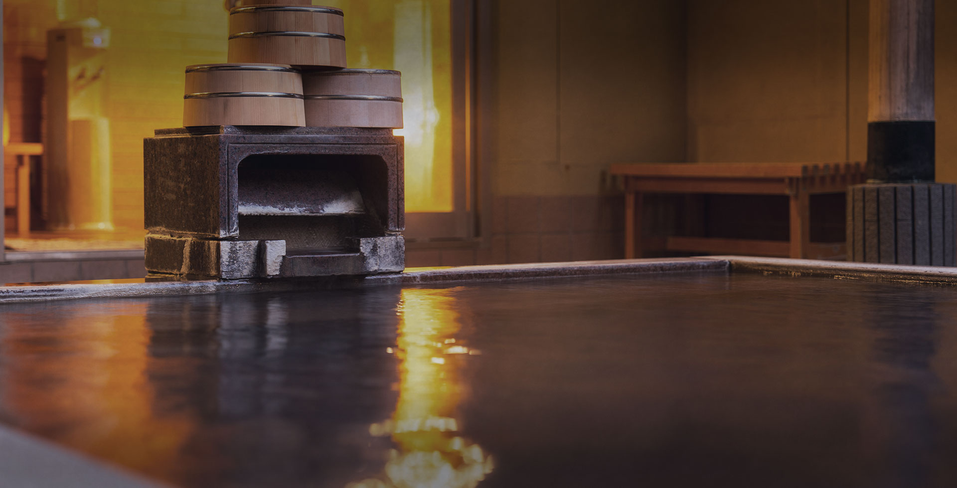 Indoor bathing pool with stacked wooden buckets and a stone heater.