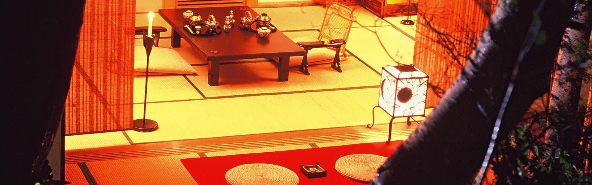Kusatsu Onsen Tenojiya tatami room with a low table and floor seating seen past an indoor tree