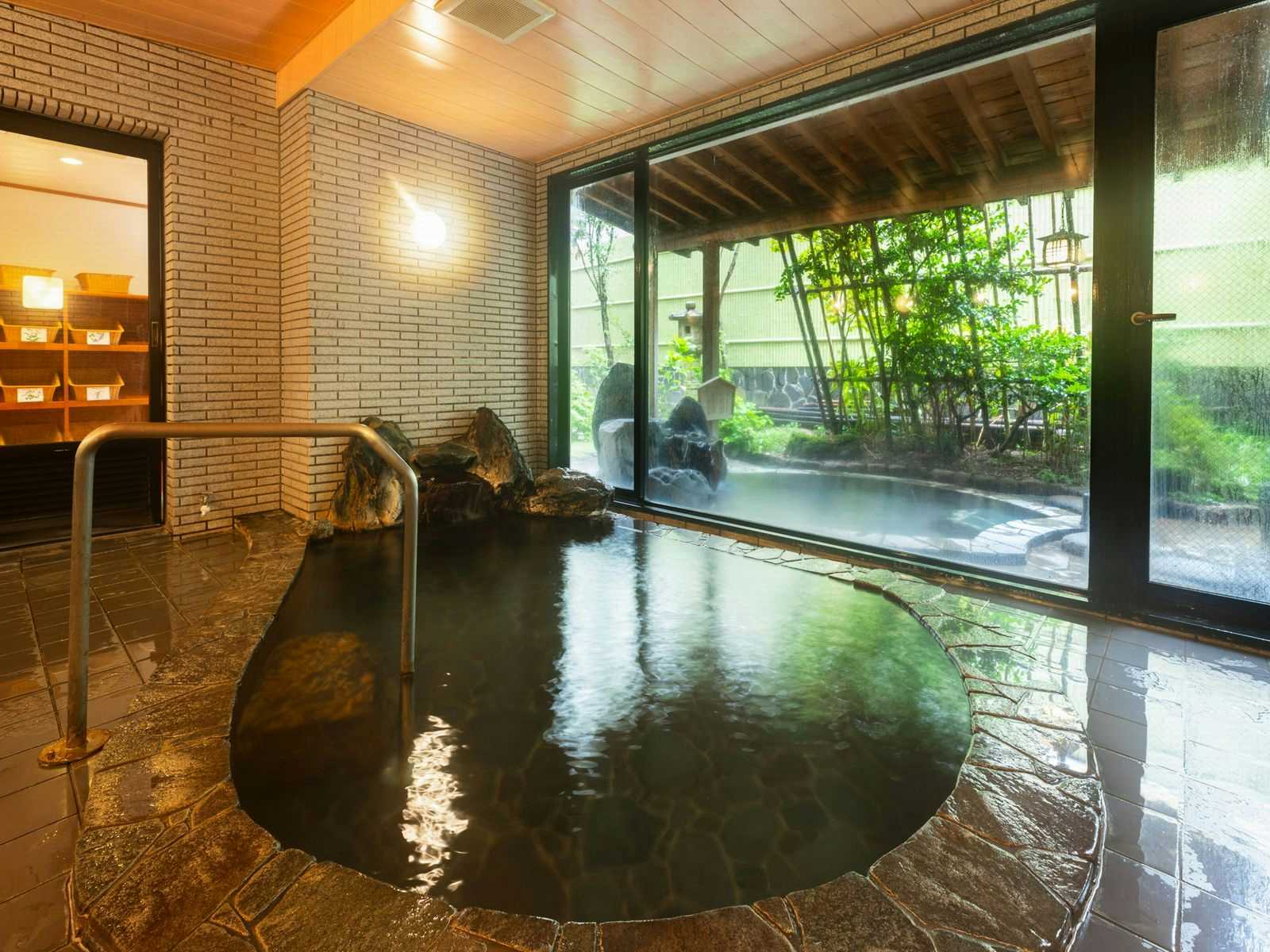 Otowaya Ryokan with a round indoor bath beside windows facing leafy bamboo.