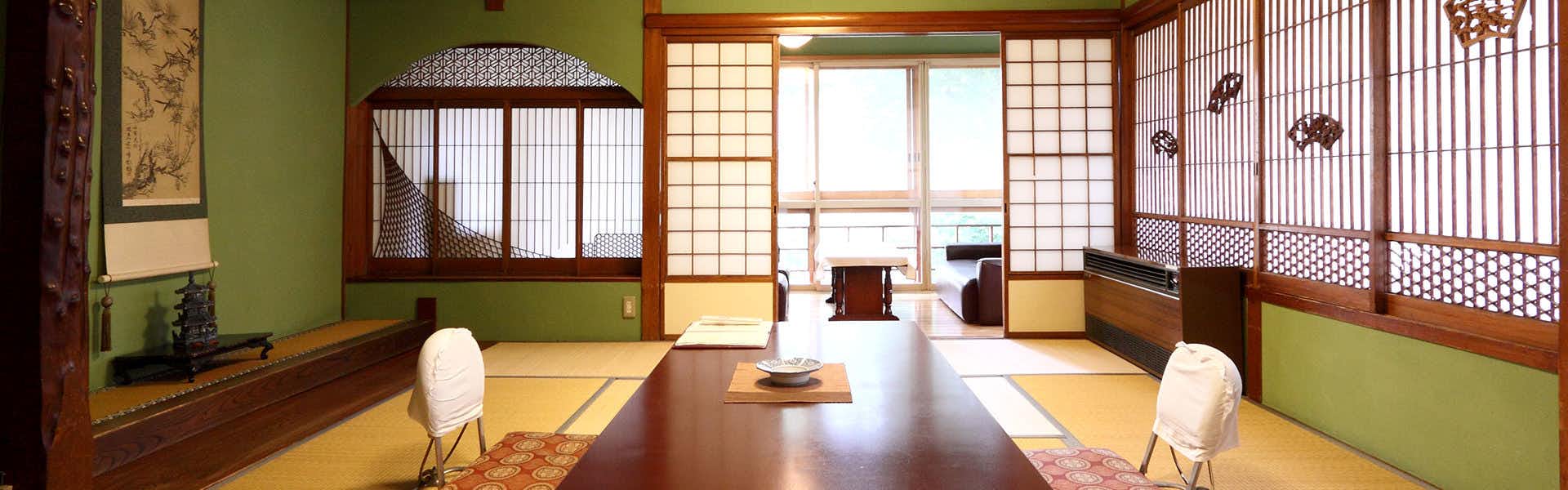 Yokotekan: An Inn of Traditional and Historic Hot Springs with an elegant tatami room with low table and decorative screens.