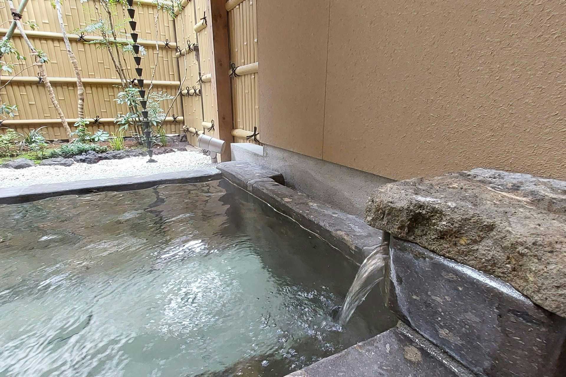 Yoshino Ryokan, a National Registered Tangible Cultural Property Inn, Hitoyoshi Onsen with a private stone bath beside a bamboo screen.