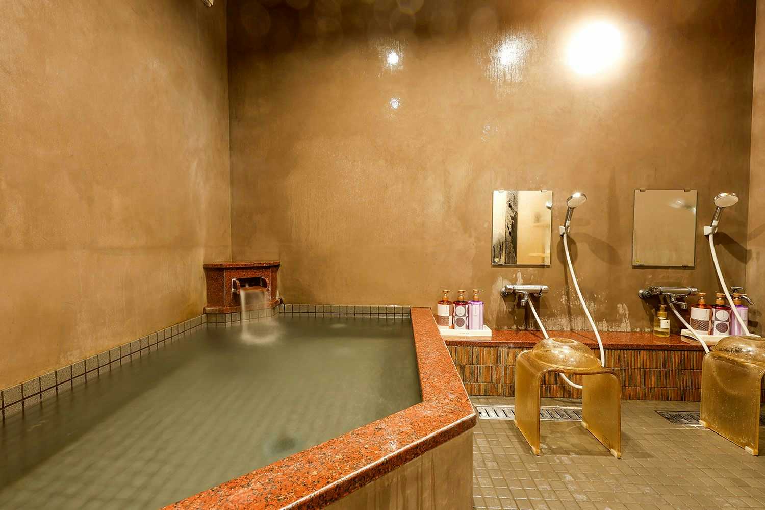 Kinosaki Onsen Yanagiso with this scene, where a tiled indoor bath includes washing stations beneath softly lit plaster walls.