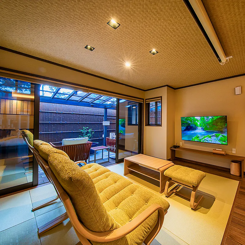 A tatami room combines a sofa, low table, television, and glass doors opening to a small terrace.