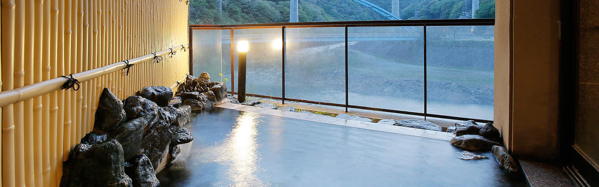 Kawaji Onsen Yukemuri no Sato Kashiwaya with a broad indoor bath overlooking forested mountains.