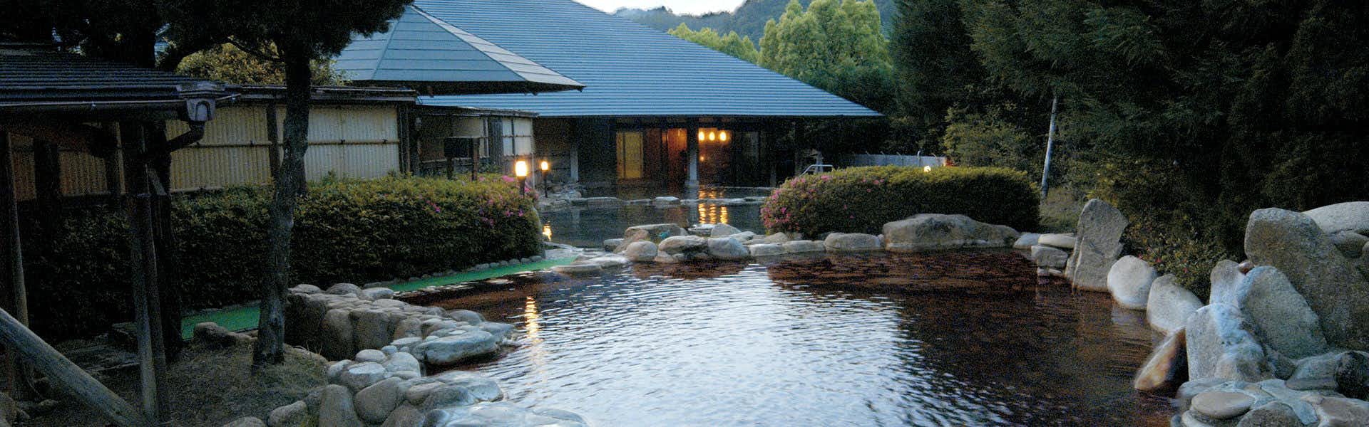Hotel Yamayuri at Watarase Onsen, Dairoten no Yado with an outdoor bath surrounded by boulders and forest greenery.