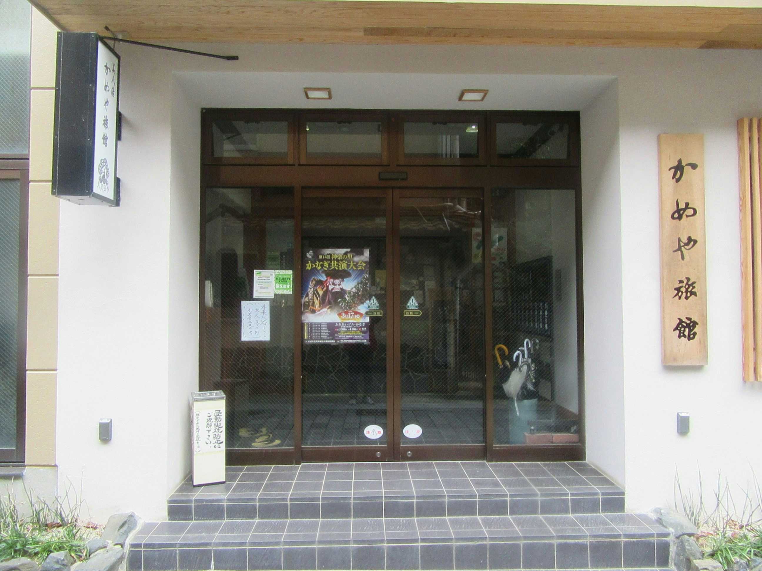 Mimata Onsen Kameya Ryokan glass entrance door beside a vertical wooden sign