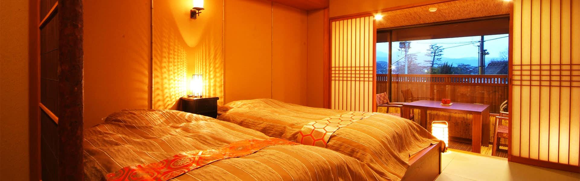 Arashiyama Onsen Saishiki no Yado Hanaikada with a traditional bedroom glowing beside mountain-facing windows.