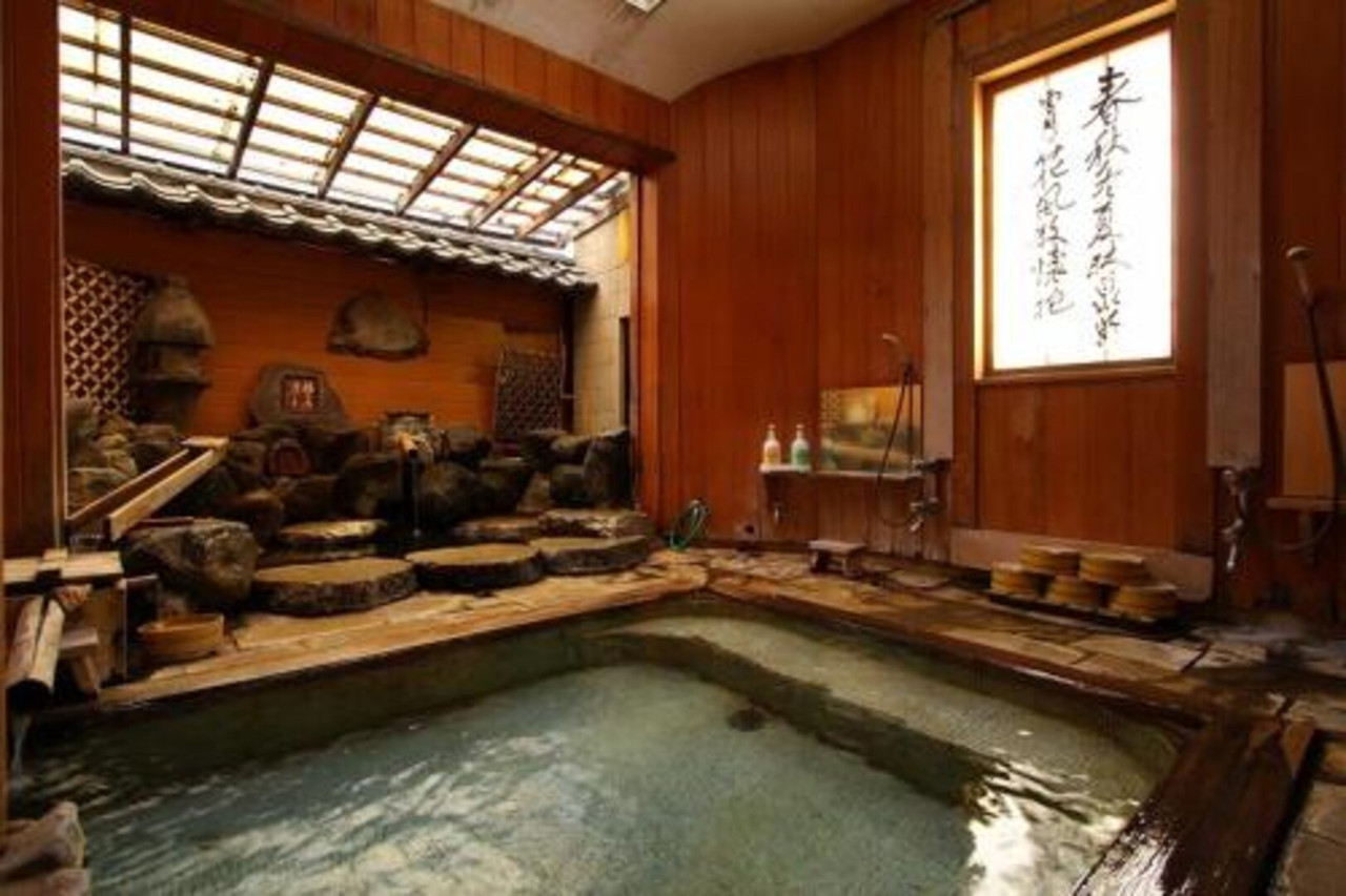 A wooden bathing room contains a stone-lined indoor bath.