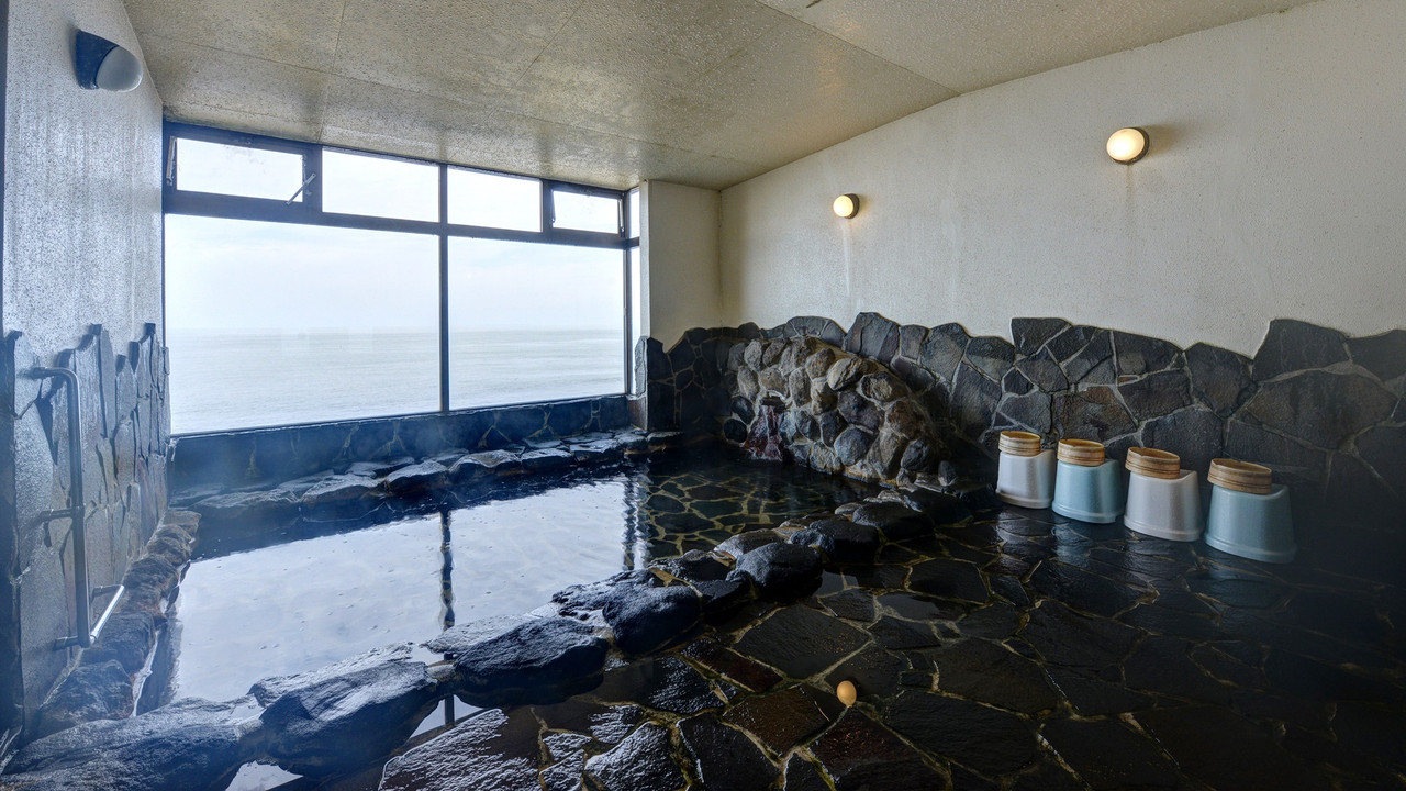 A spacious stone bathing pool with windows and a view outside.