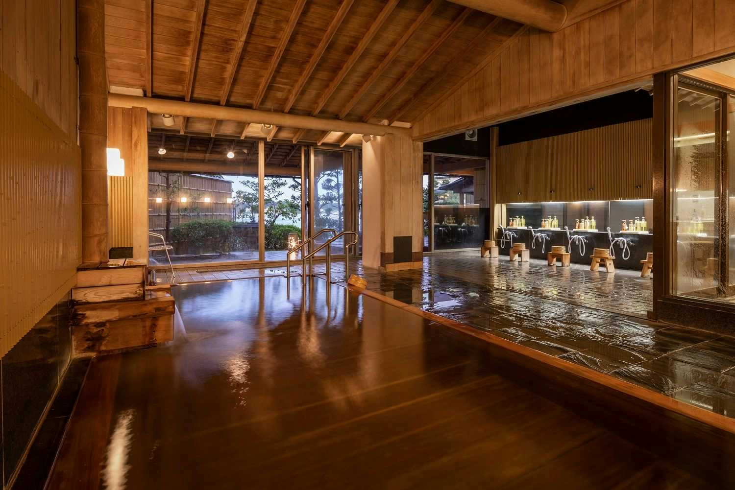 Sansuikan Kinryu with this scene, where a timber-framed indoor bath opens directly toward Lake Hamana at dusk.