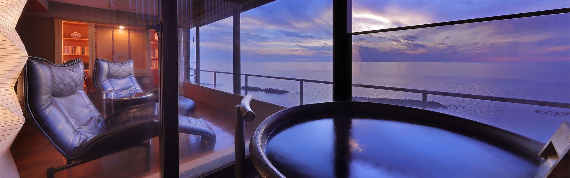 Yusuitei Isagoya Interior with large glass panels revealing water and distant landscape, curved seating form in foreground, blue-purple lighting throughout