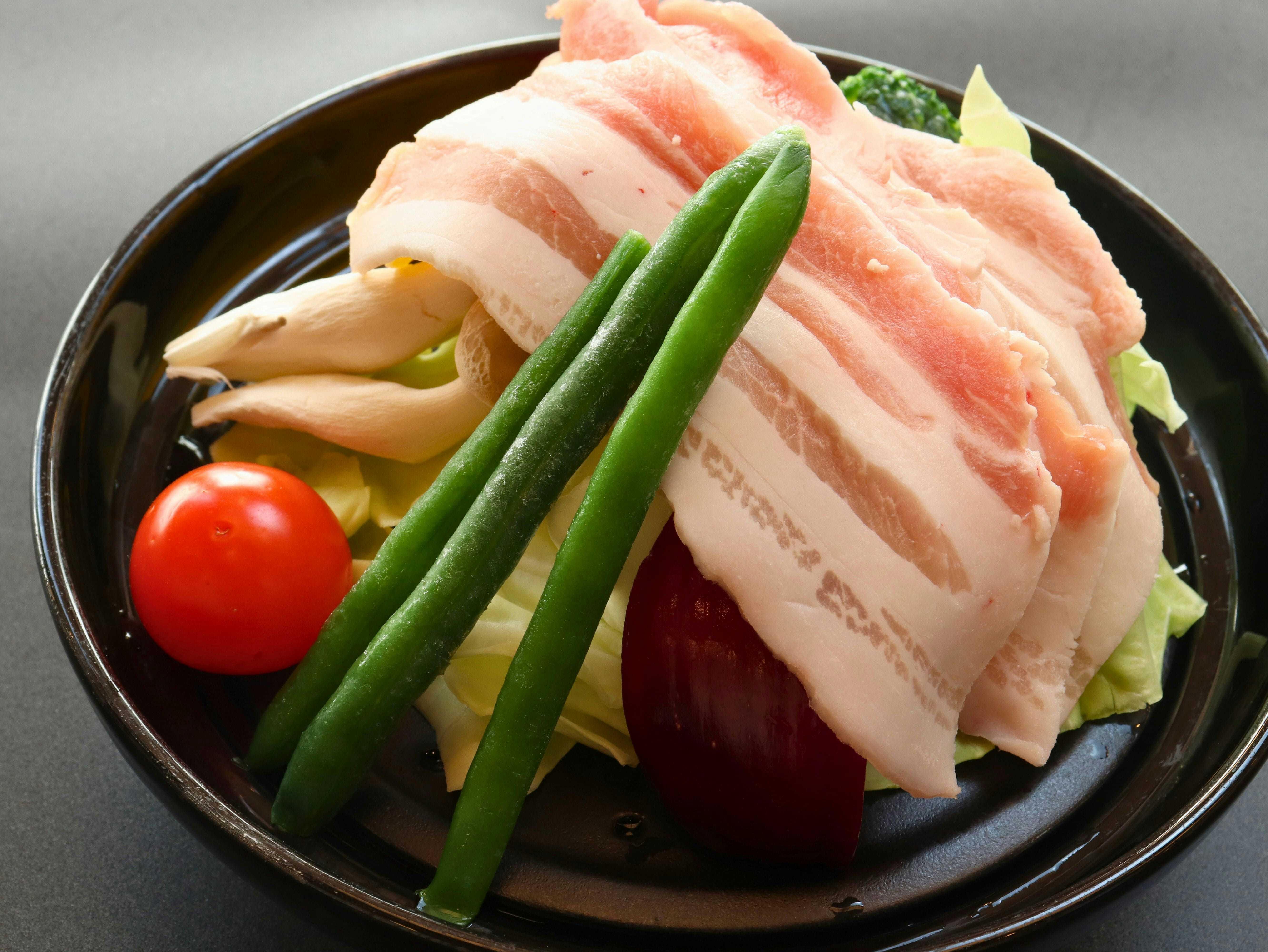 Three Private Hot Spring Baths with Free-Flowing Water - Yuyado Onsen Taiyokan with sliced pork and green vegetables on a black plate.
