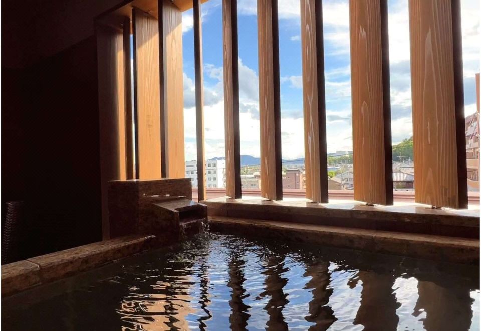 An indoor bath beside tall windows.