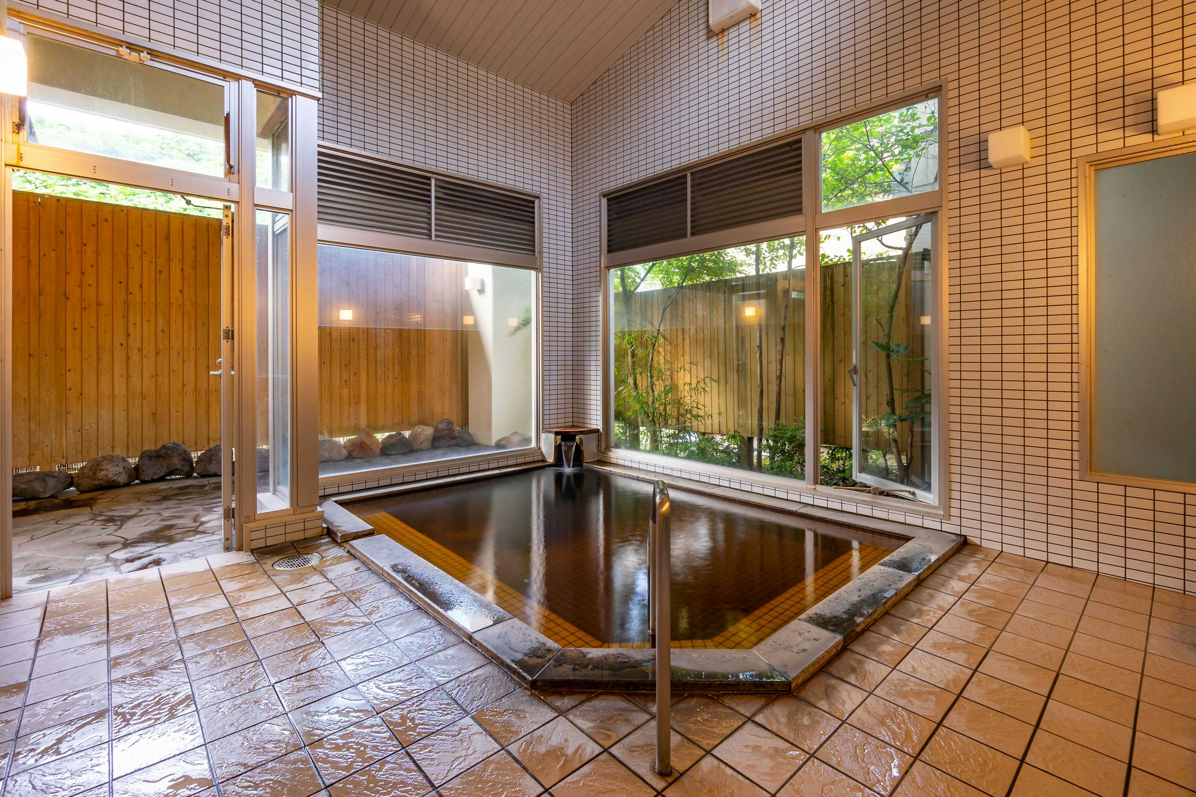 Kyuden Ryokan with an indoor soaking bath beside courtyard windows.