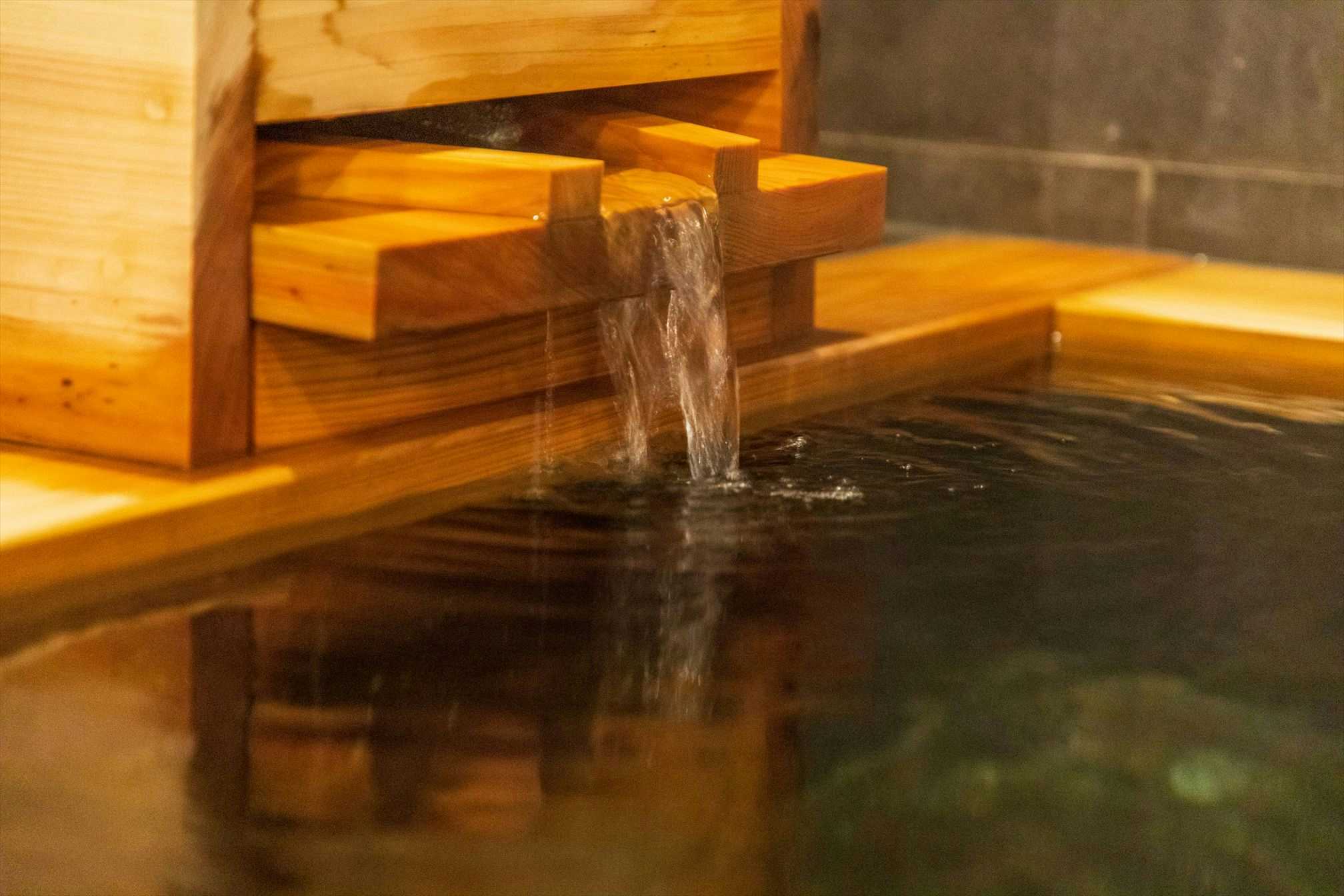 Atami Onsen Yamaki Ryokan with a timber soaking bath filled by a wooden water spout.
