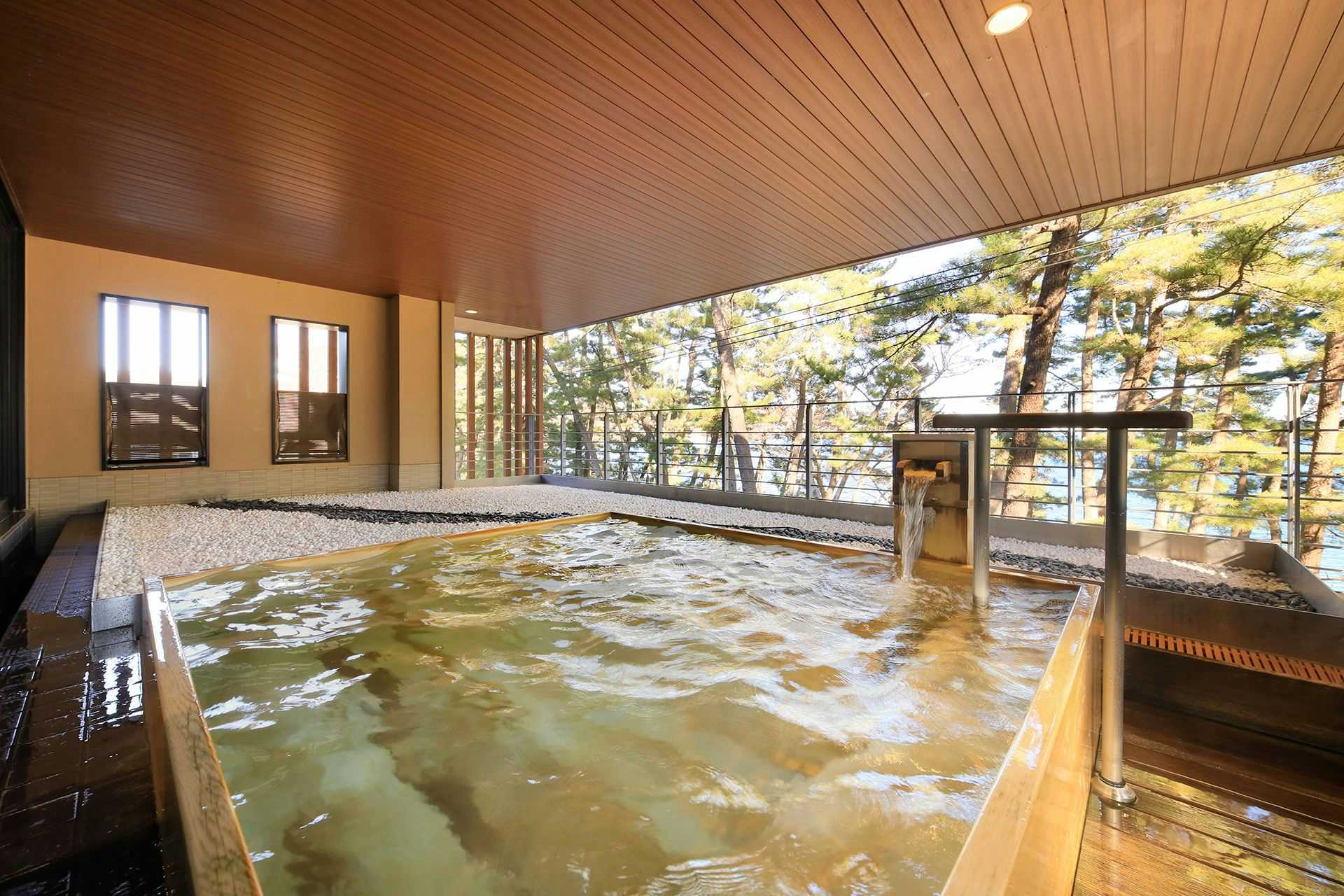 Hamabe no Ryori Yado Houraikan with an open-air mineral bath facing tall seaside pines.