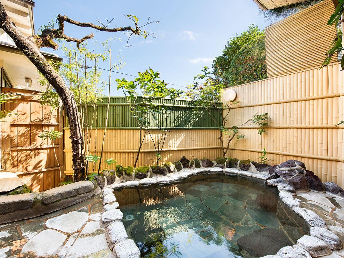 Hakone Ohiradai Onsen Yunohana with an open-air mineral bath beneath leafy garden trees.