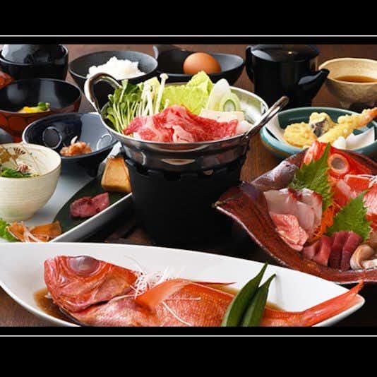 Small hot spring inn Mitaniya with a dinner spread with grilled fish, hot pot, sashimi, and vegetables.