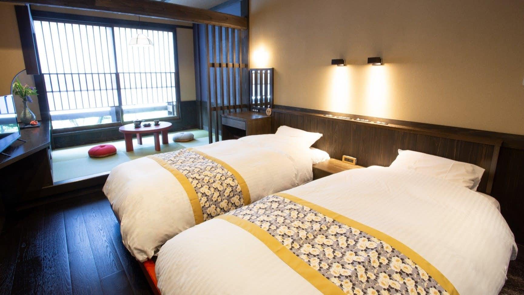 Kurokawa Onsen Ryokan Misato with a twin bedroom with pale timber walls and floral runners.