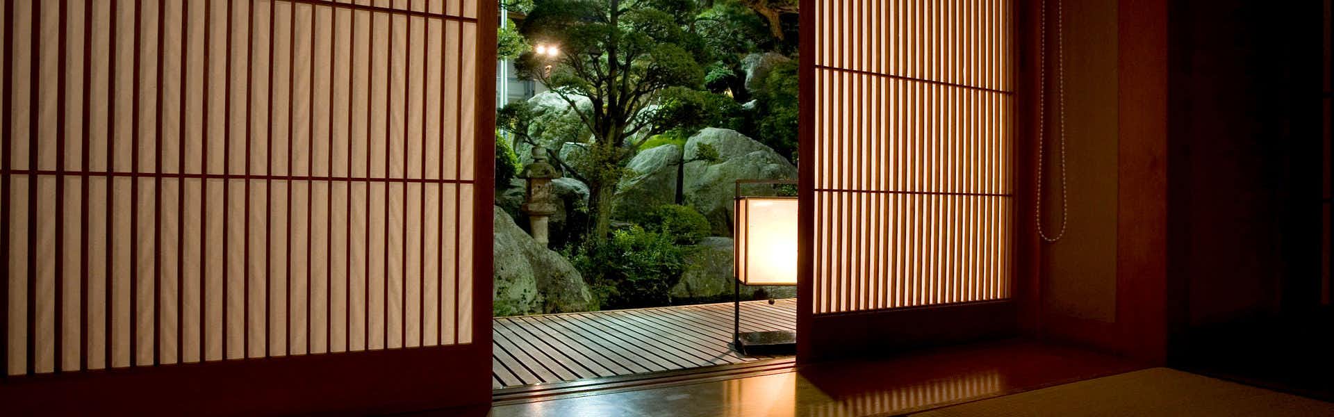 Meiseki no Yado Kagetsu with an open shoji doorway framing a lantern-lit garden path.