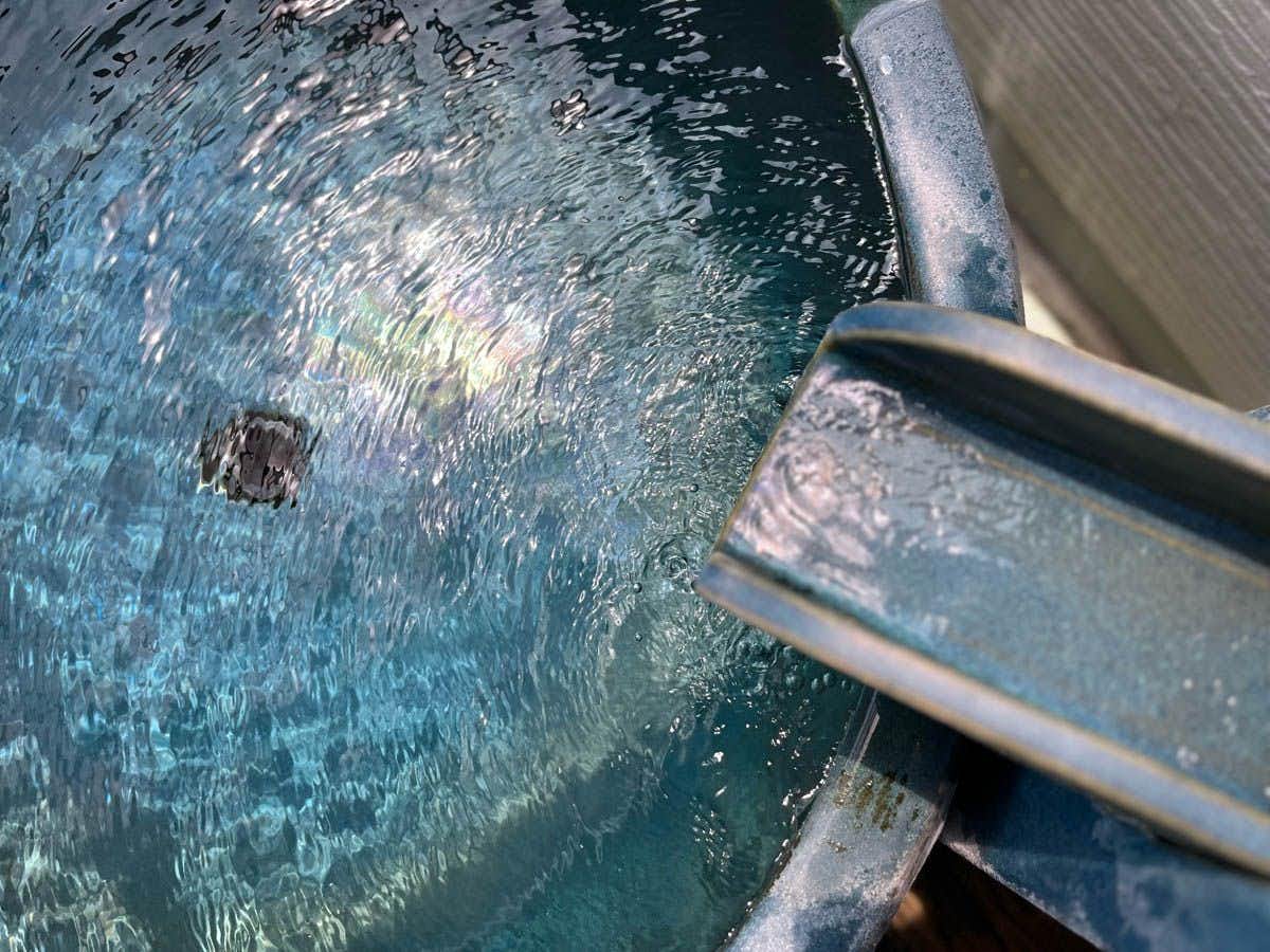 The Origin of Ueki Onsen - Ryokan Matsunoyu with clear bathwater swirling around a dark metal spout.