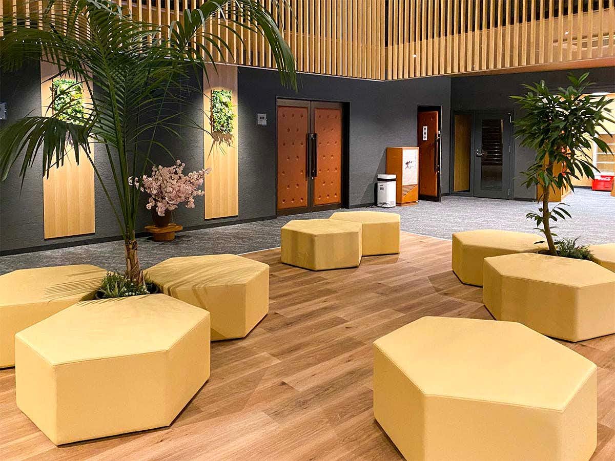 Maruoka Onsen Takekurabe with a modern lobby with geometric seating and potted palms.