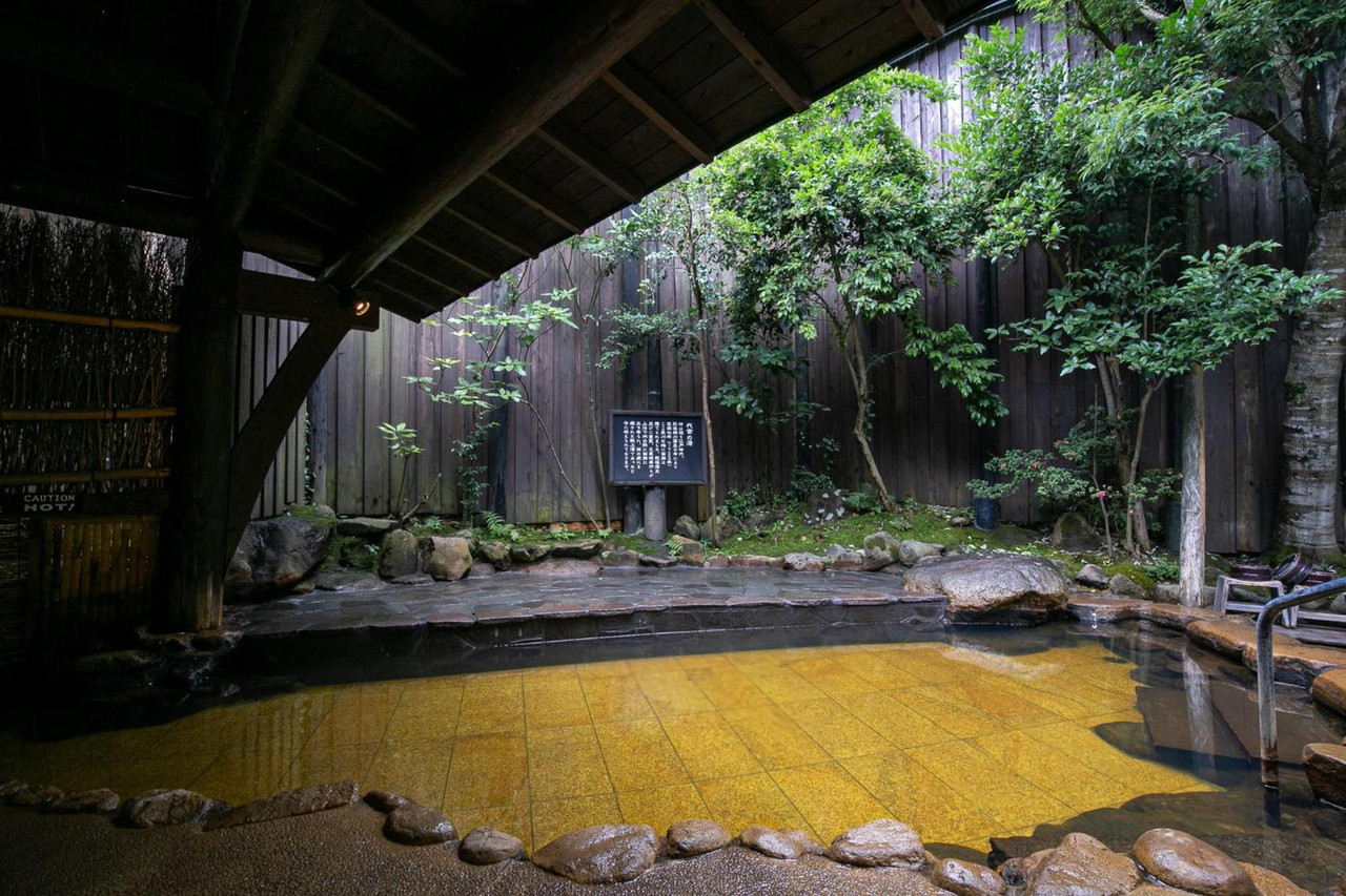 A covered rock-lined bath in a wooded setting.