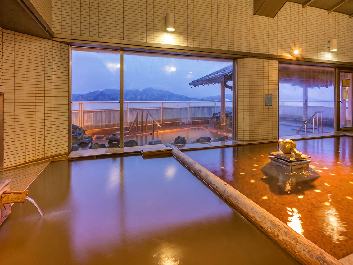 An indoor amber-colored bath beside broad windows at dusk.