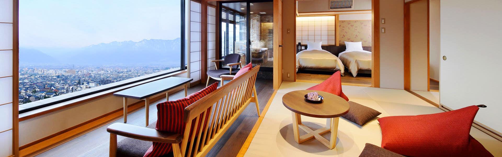 Shinshu Matsumoto Utsukushigahara Onsen Shouhou with a refined suite with lounge chairs and panoramic windows.