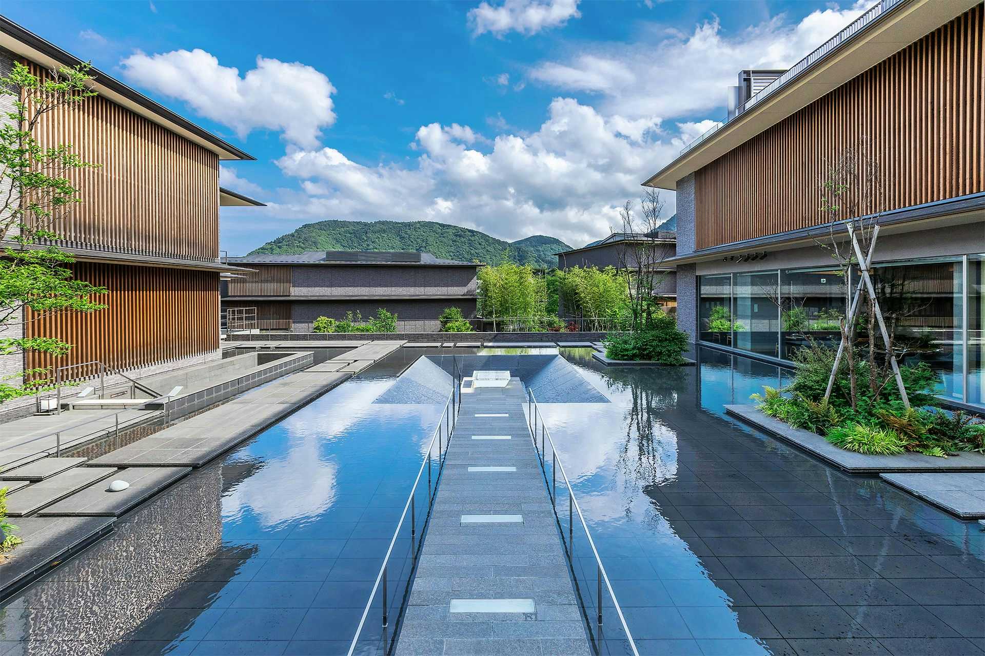 A long reflecting pool framed by timber buildings.