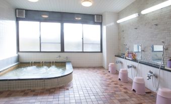 An indoor tiled bath with frosted windows and washing stations.