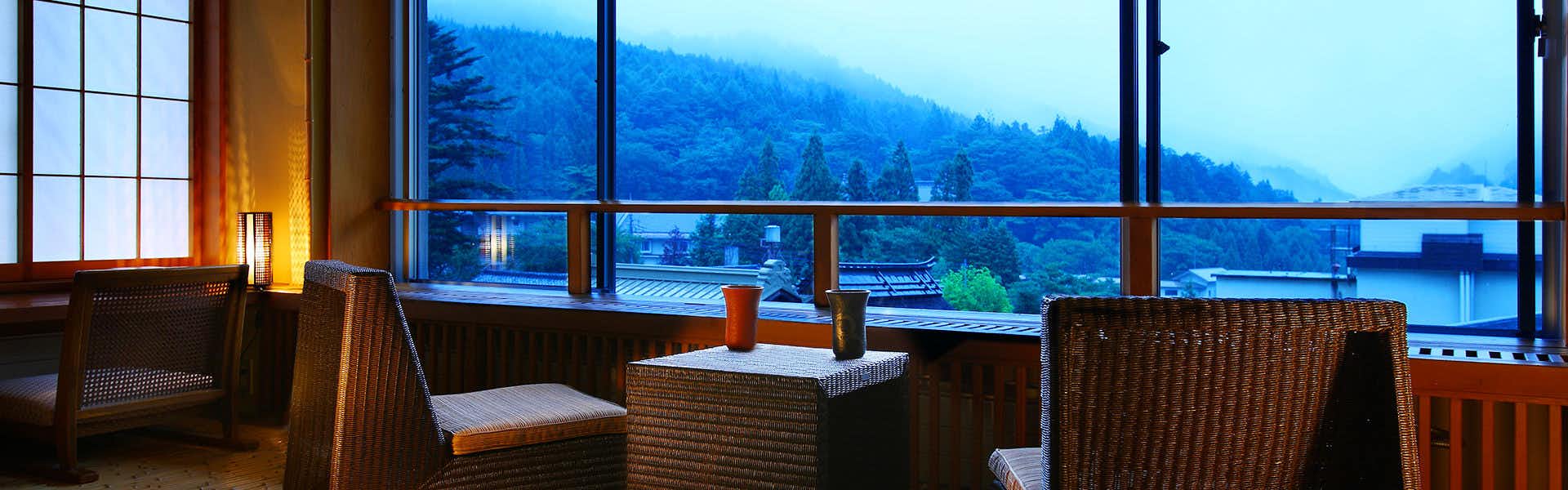 Shima Tamura: A Hot Spring Paradise Inn with a window lounge overlooking blue mountain ridges.