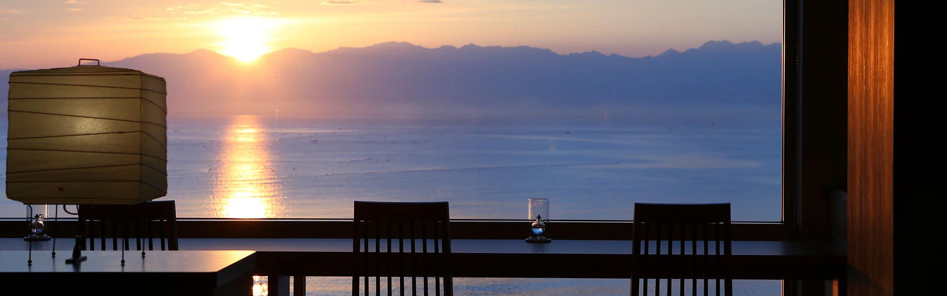Himi Onsenkyo Relaxing Inn Umikari with the golden sunset reflected across calm coastal water.