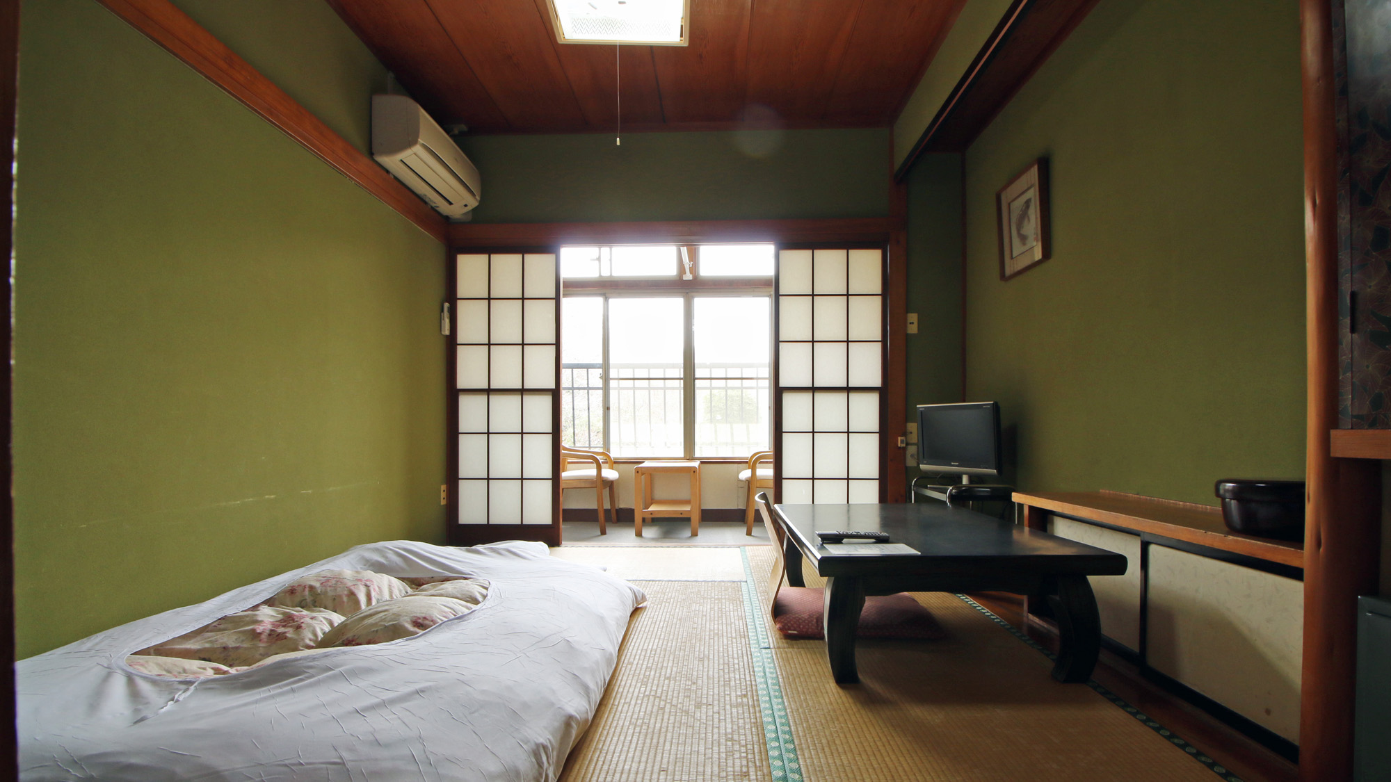 A traditional room with bedding, a low table, and a balcony.