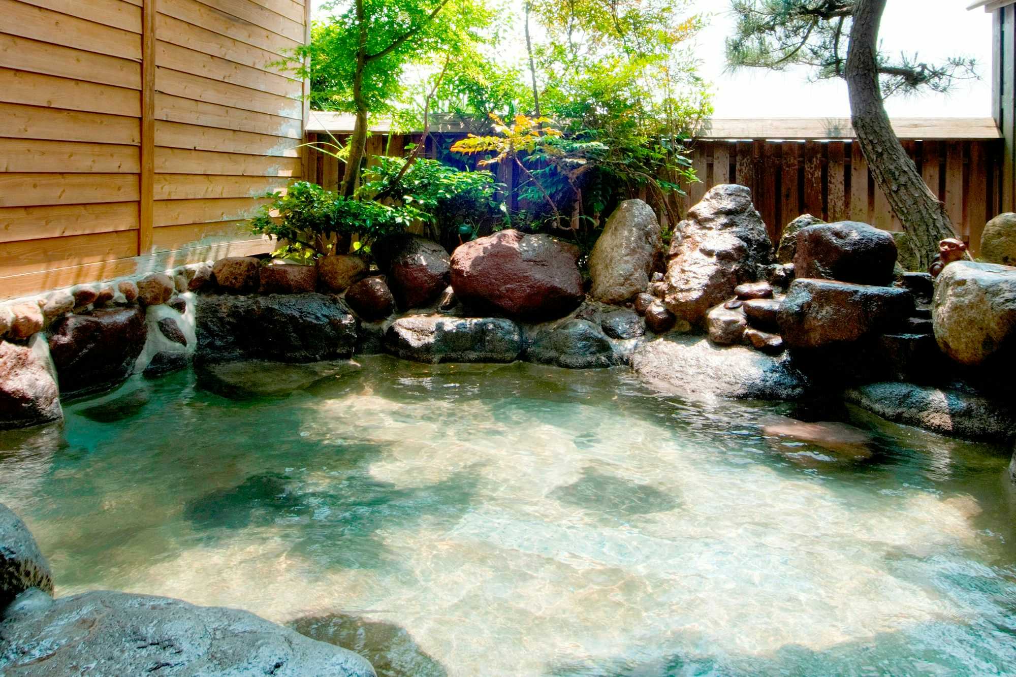 Kamioka Onsen Hozanso with this scene, where a milky blue outdoor rock bath sits inside a private wooden enclosure.