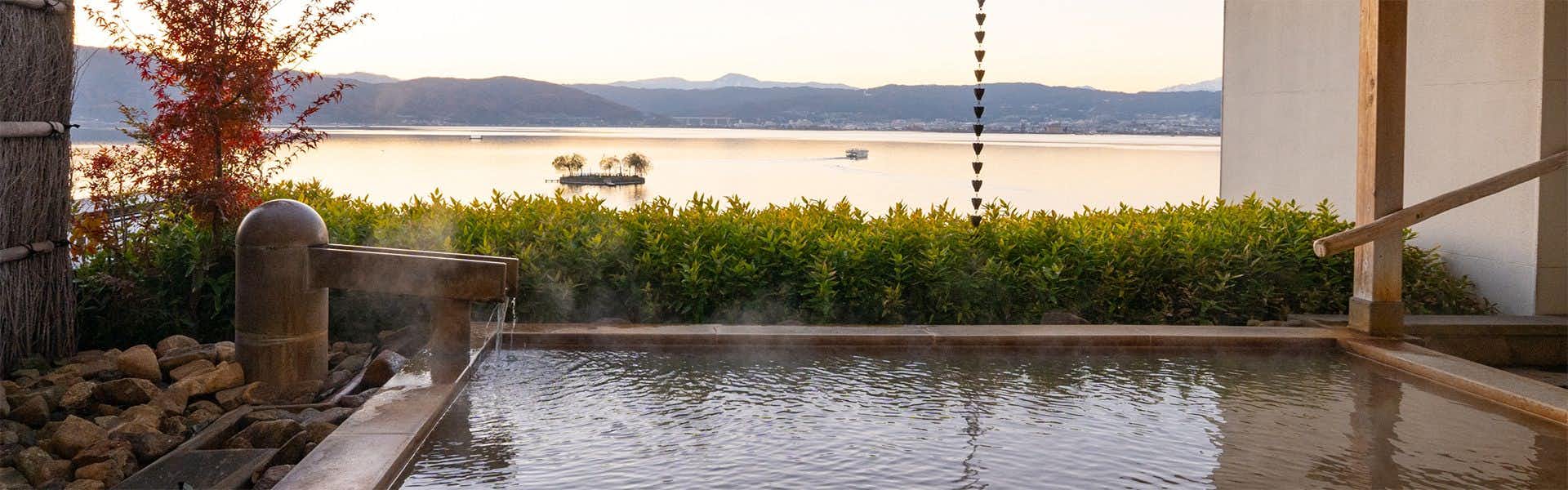 SUHAKU with an open-air bath overlooking Lake Suwa and distant mountains.