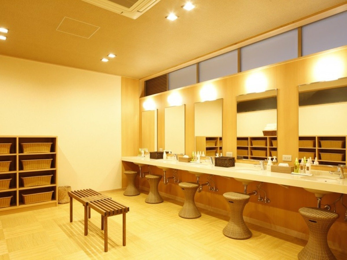 A row of mirrors and stools along a wooden vanity counter.