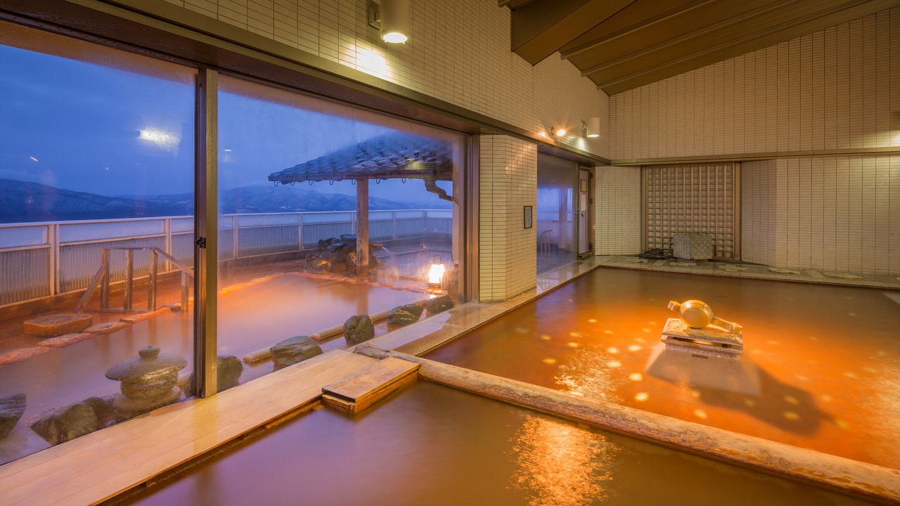 An indoor bath with a stone feature and windows opening onto a terrace.