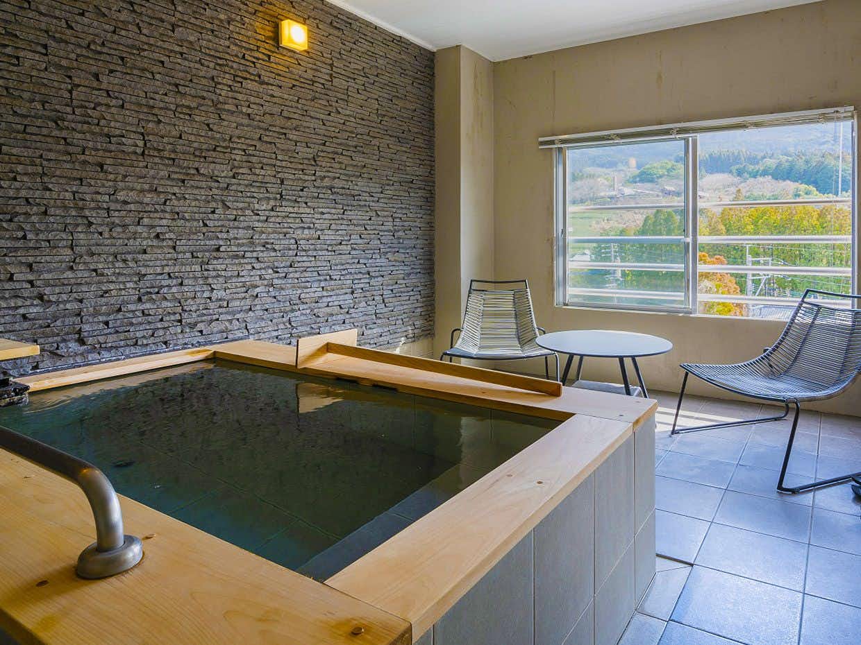 Saga Beef Inn Koyokaku with this scene, where a private rectangular bath adjoins an airy guest room with river-facing windows.