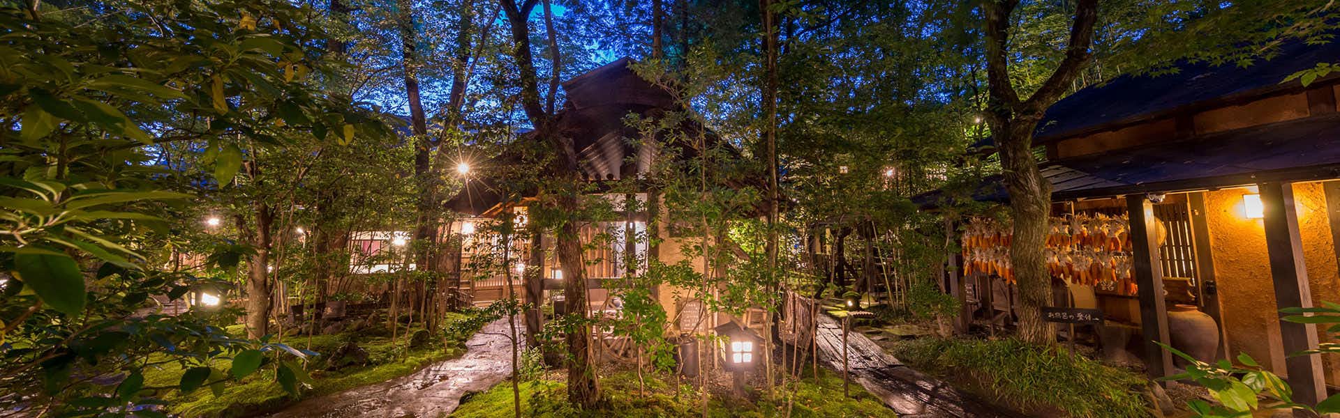 Kurokawa Onsen Oyado Noshiyu lantern-lit garden and timber lodging buildings at night