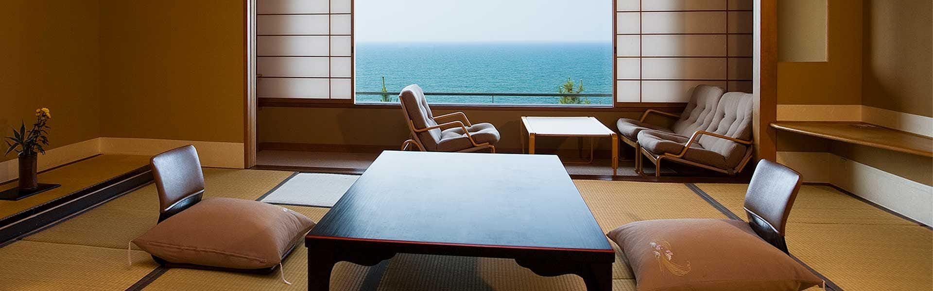 Kasuitei Seating space with dark table, cream upholstered chairs, wooden posts, large window opening, light floor matting