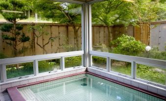 An indoor bath with windows overlooking a garden.