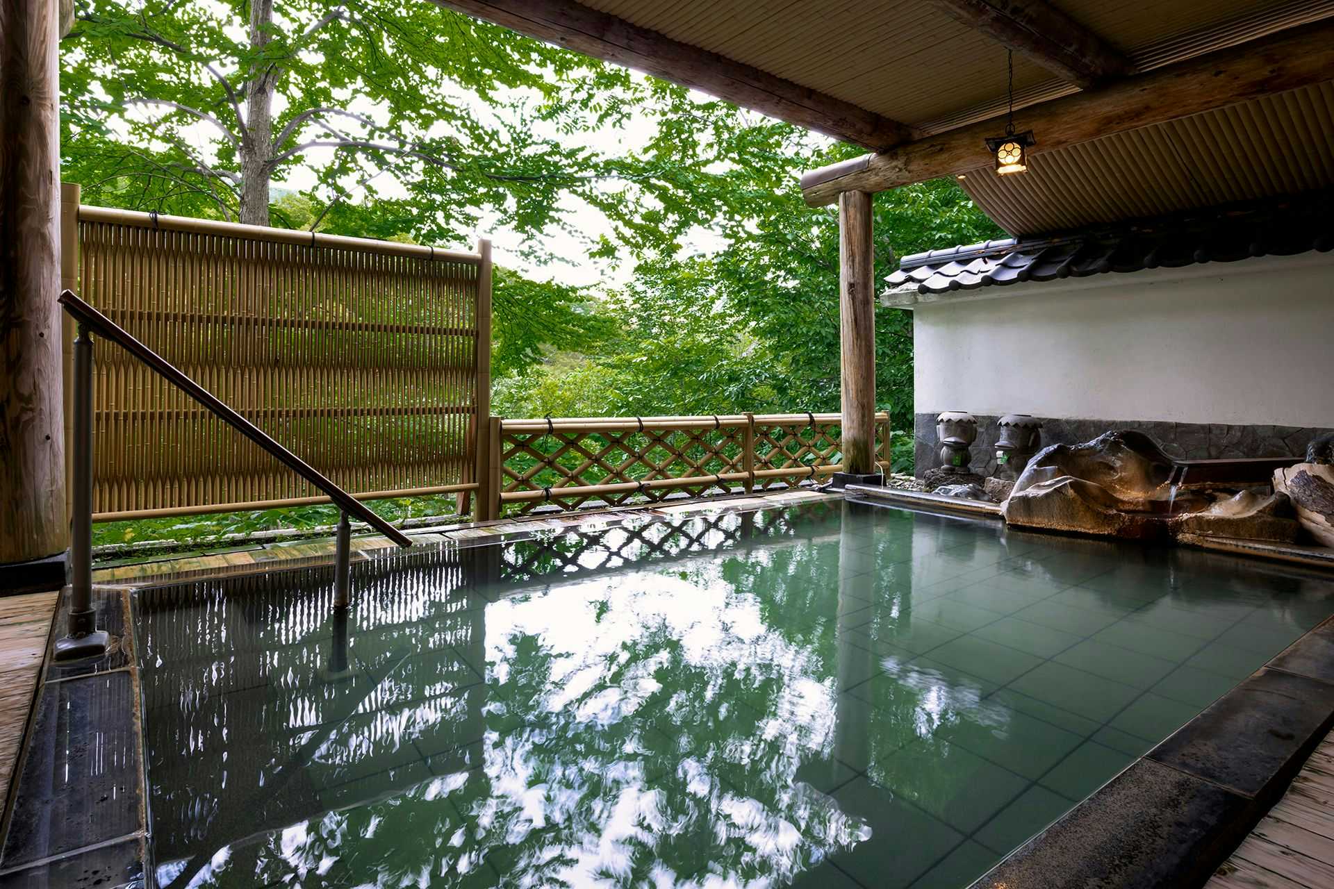 Shogetsu Grand Hotel with an open-air mineral bath overlooking forest foliage.