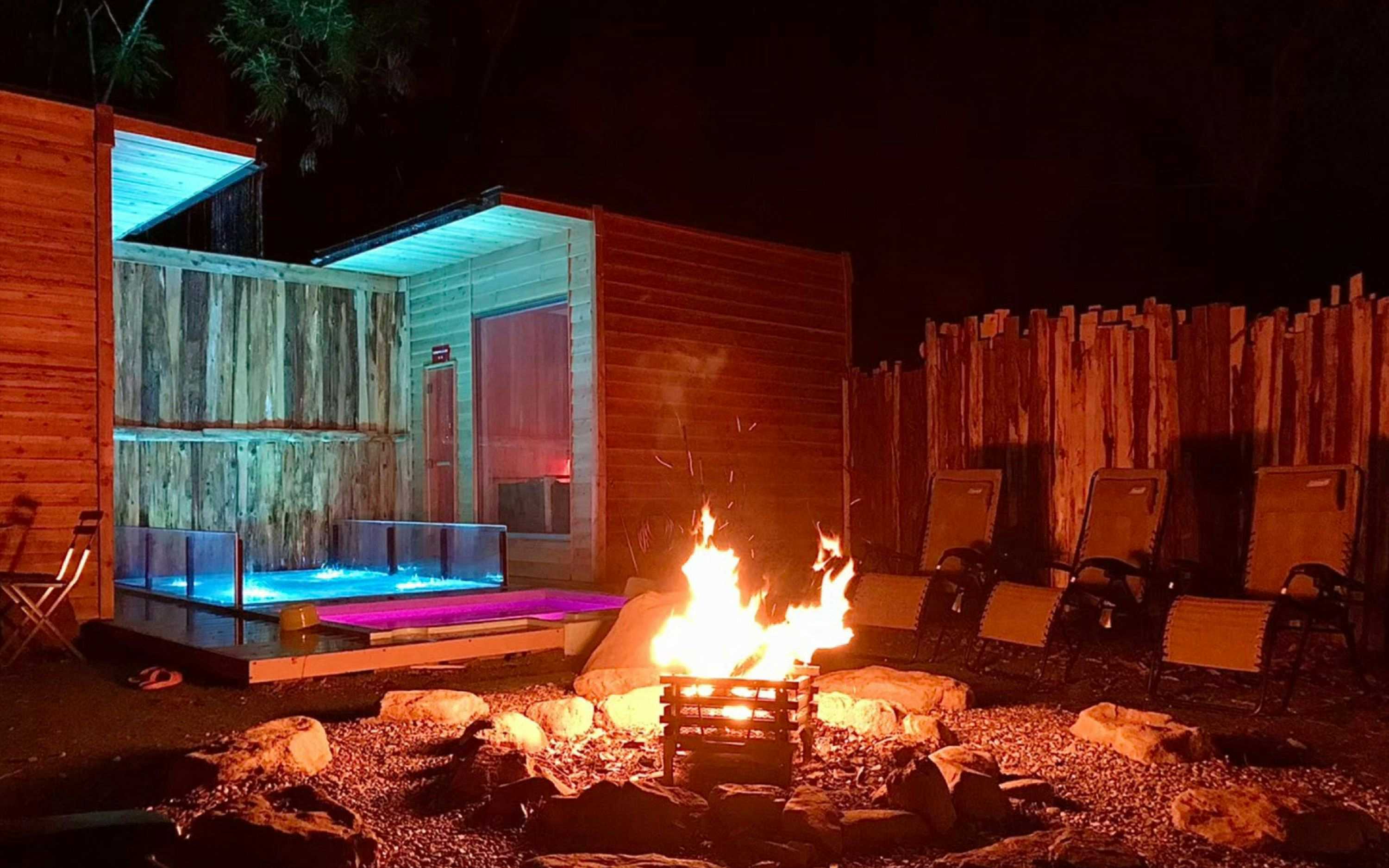 Umeno-ya Resort Matsukawa-kan with a glass-fronted sauna glowing beyond an outdoor fire pit.