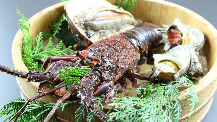 A lobster and shellfish arranged in a wooden tub with greenery.