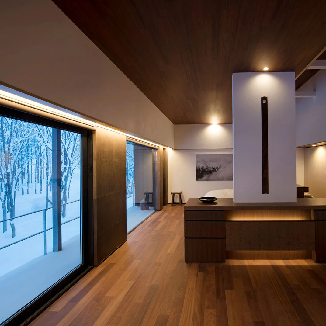 Villa interior at Zaborin with dark timber ceiling and floor-to-ceiling windows framing a snow-covered birch grove