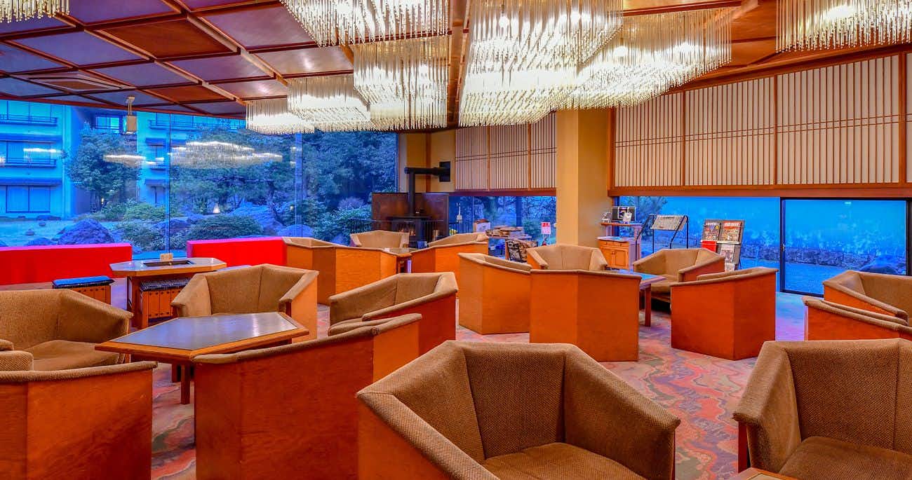 A broad lobby lounge with orange chairs and garden windows.
