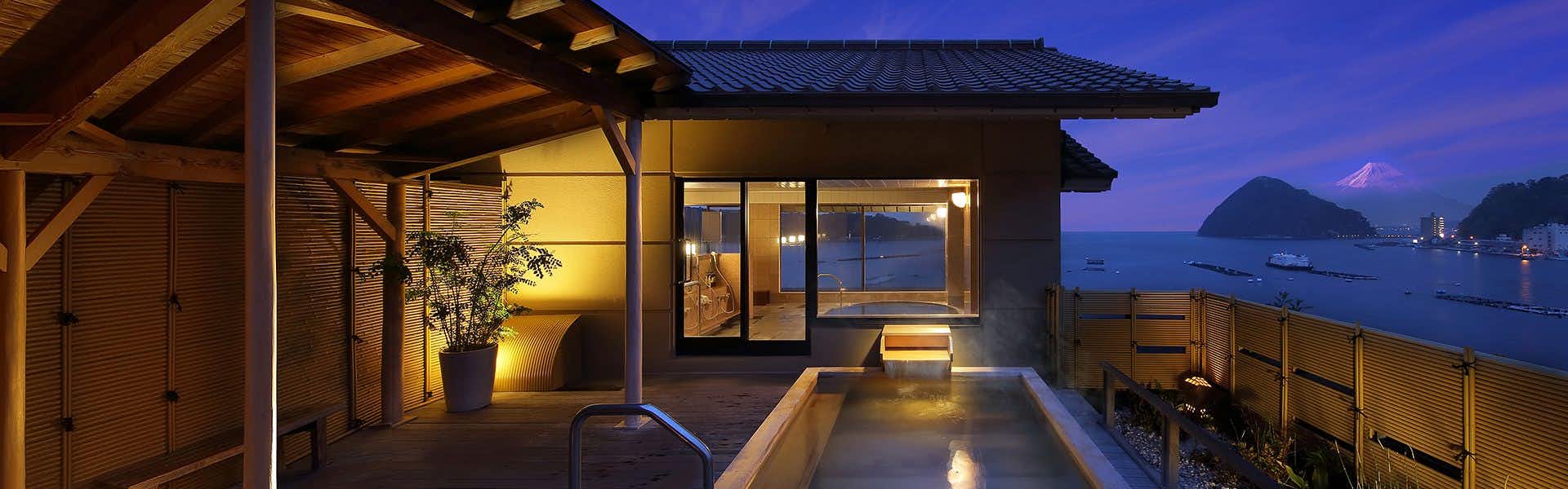 Shoutoukan with this scene, where its open-air bath sits beneath timber eaves with the bay beyond.